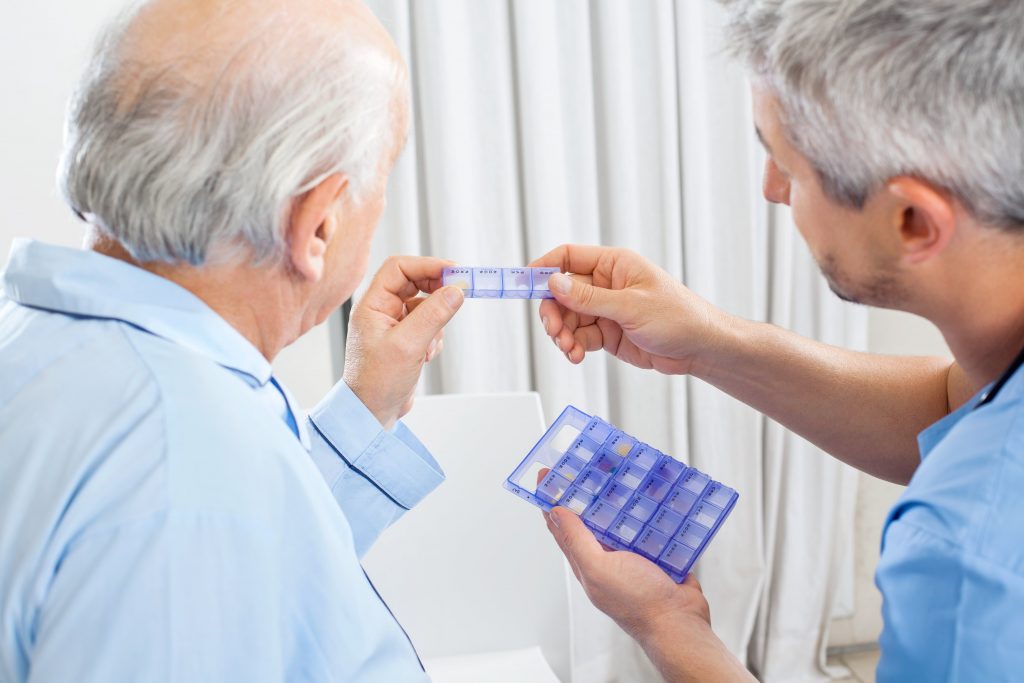 carer helping a man to take his medication