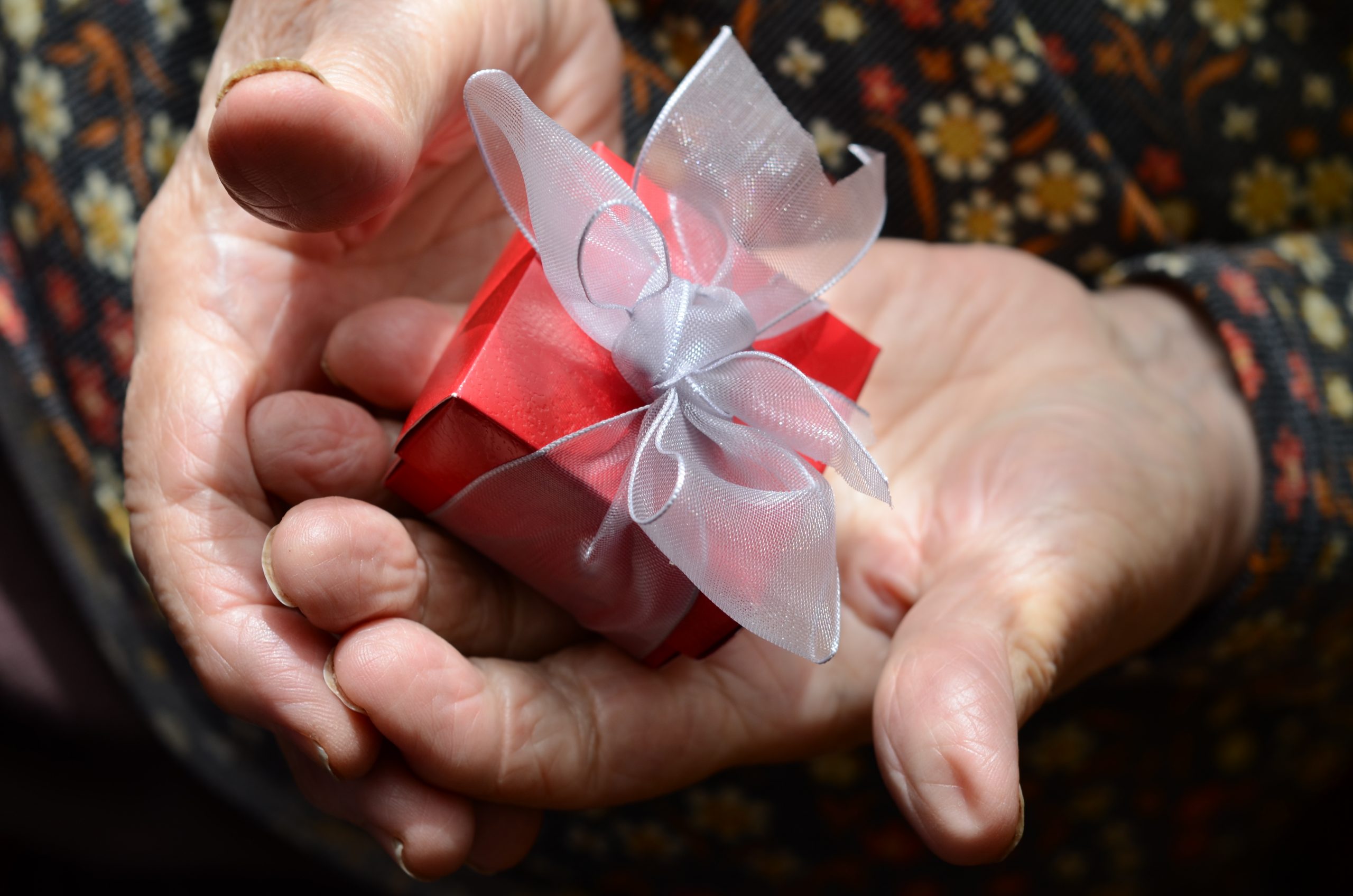 lady with dementia holding a red present box which is wrapped with a bow