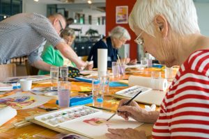 people with dementia sat at a table painting with watercolours