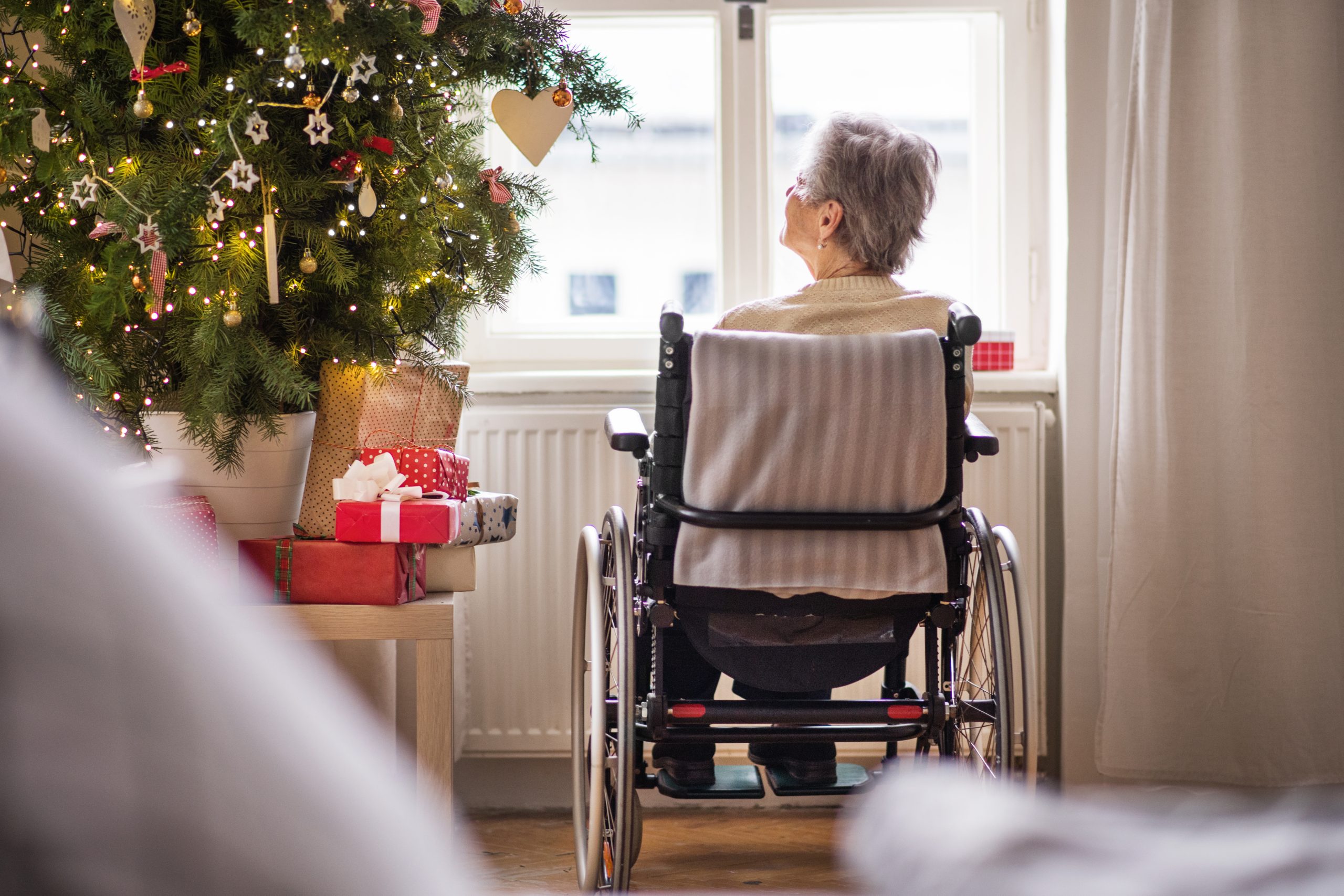 Elderly lady alone sat in wheelchair looking out of the window