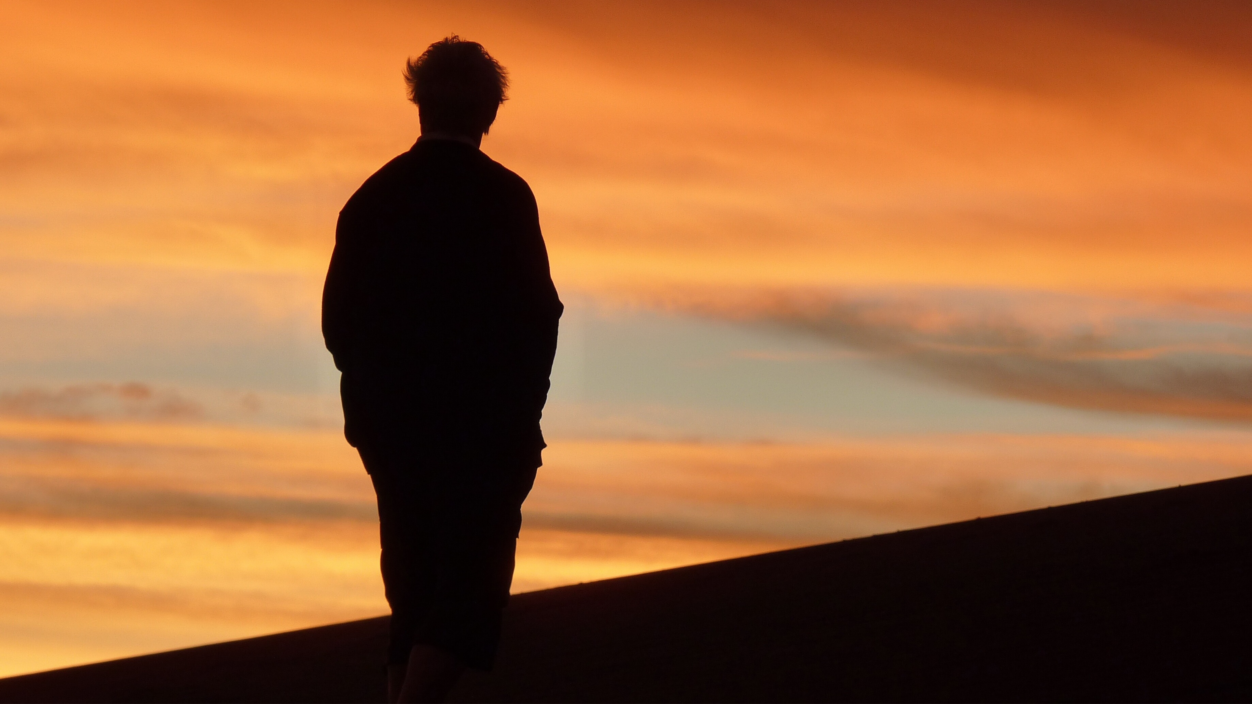 man with dementia silhouette of him standing on a hill as the sun goes down