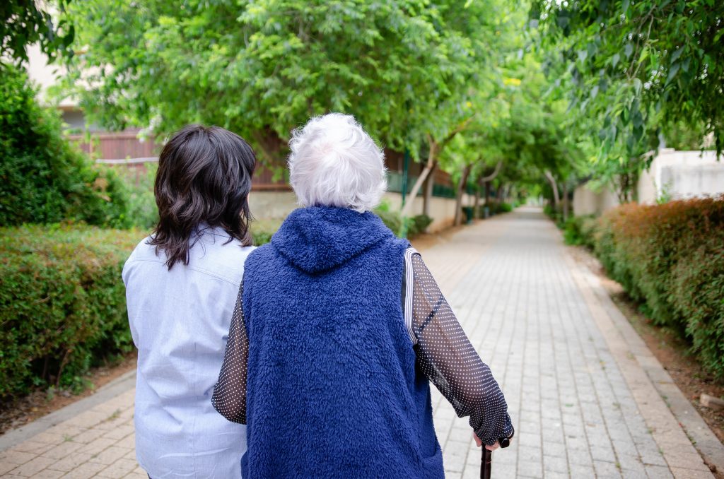 lady with denetia walking outside with her carer