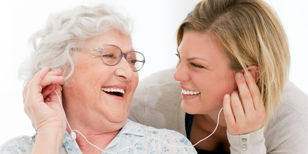 lady with dementia listening to music through head phones with grandaughter