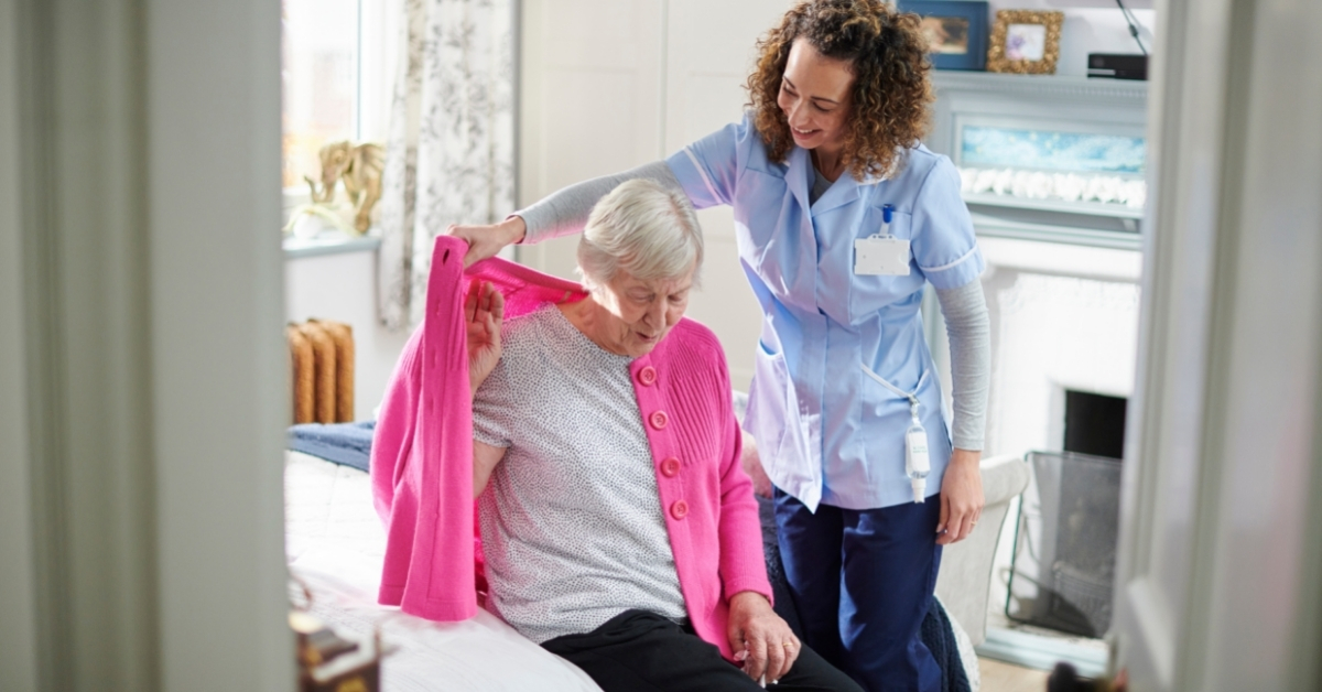 Carer helping a client to put on her cardigan