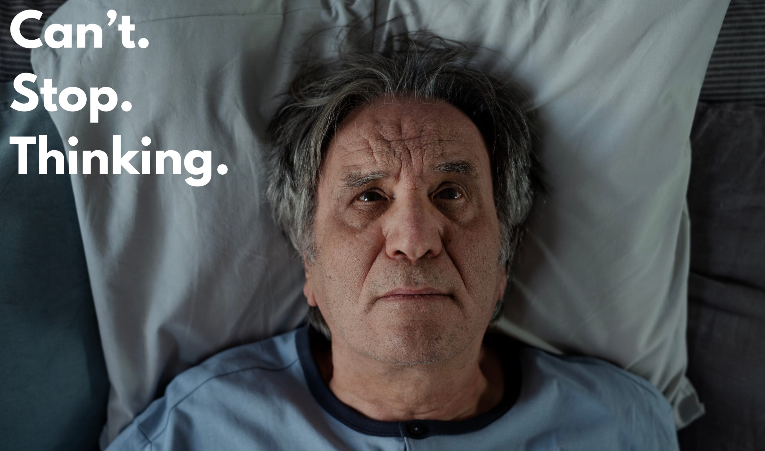 Older man lying awake in bed unable to sleep, representing mental load and stress of caregiving.